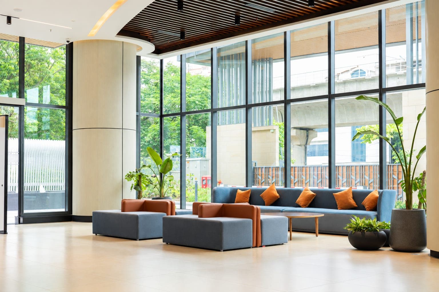 Sunlit lobby with floor-to-ceiling windows and plants at Clayworks Senate, Bengaluru