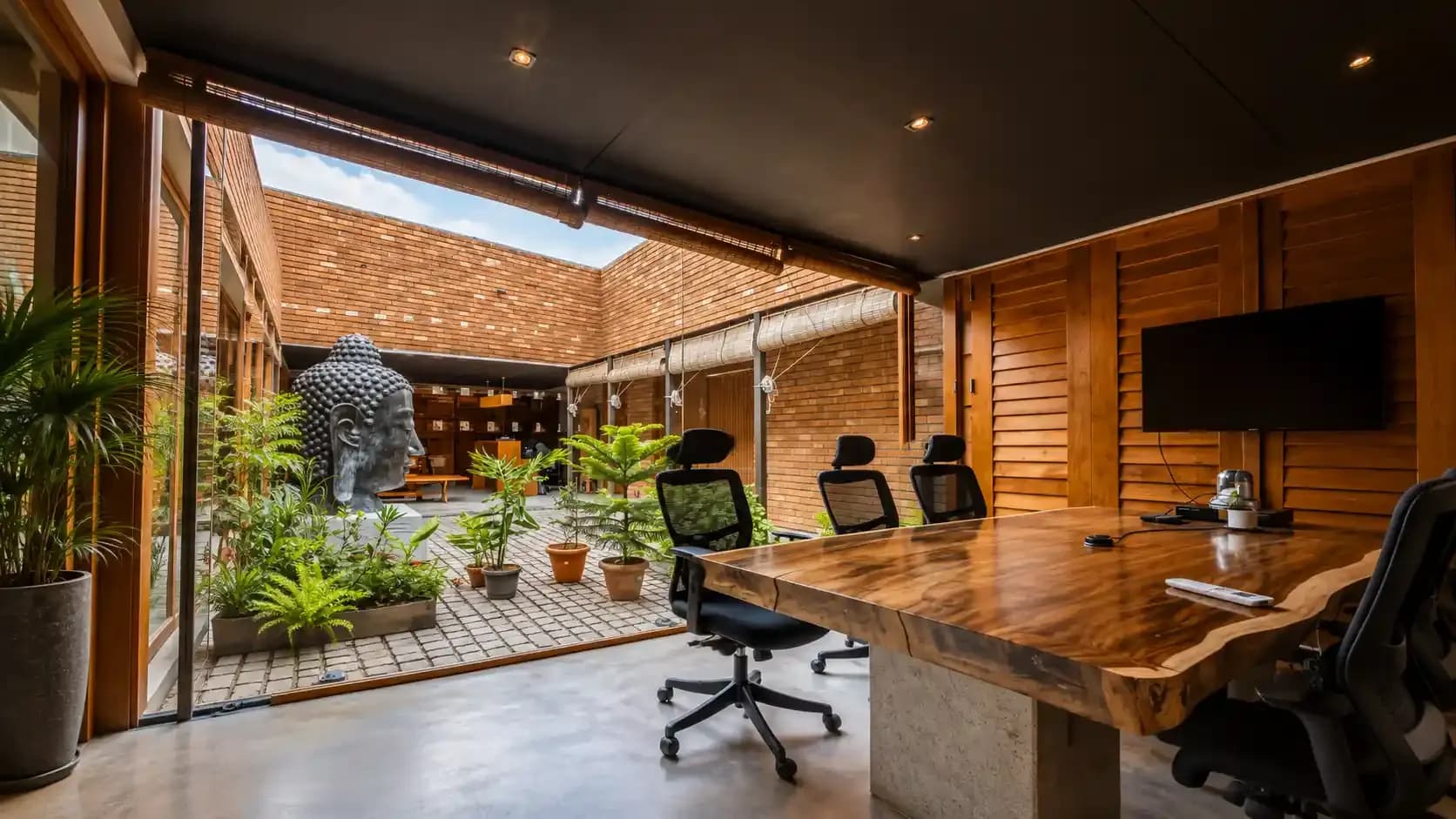 ClayWorks meeting room with a live-edge wooden table opening onto a brick courtyard garden